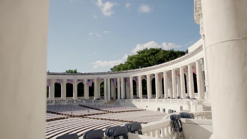 Flags wave as they hang from the portico of an amphitheater on a sunny day