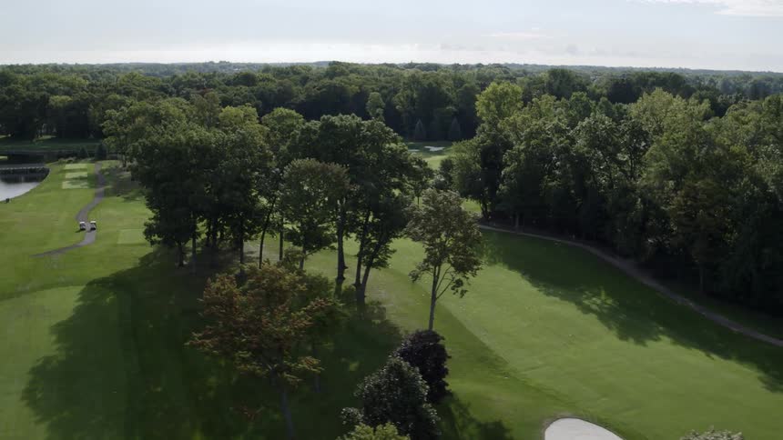 The golf course has many tall trees