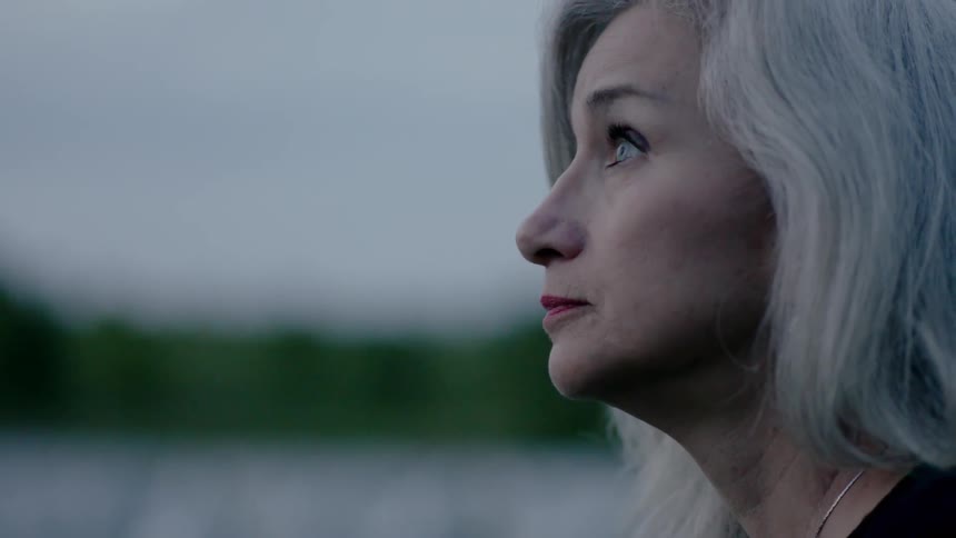 A woman with grey hair is looking up at the sky