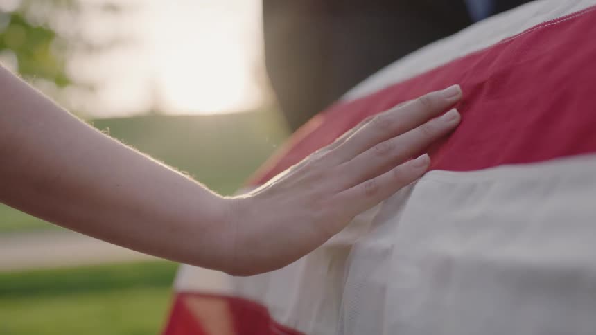 A woman presses her hand on a flag draped casket