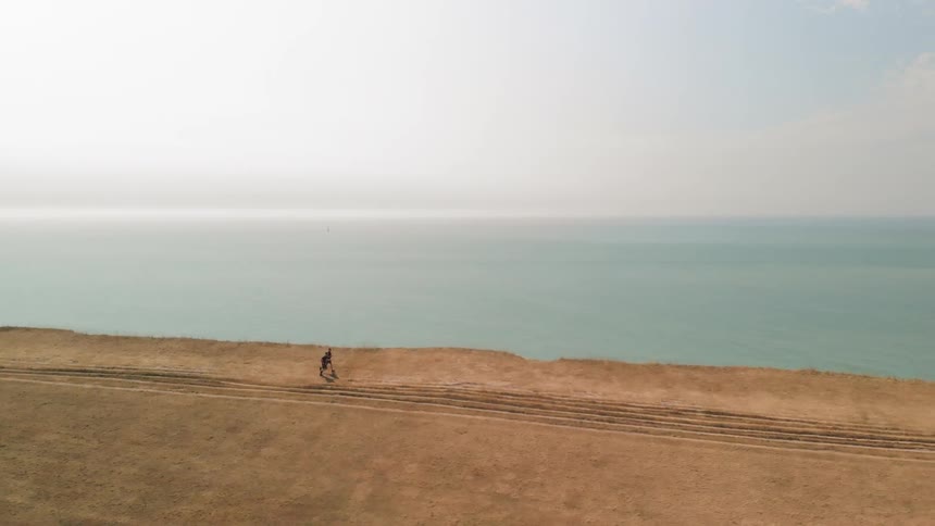 Two Athletes Running by White Cliffs on a Sunny Day