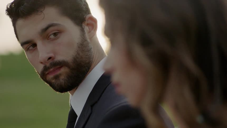 A man looks over at a grieving woman outdoors