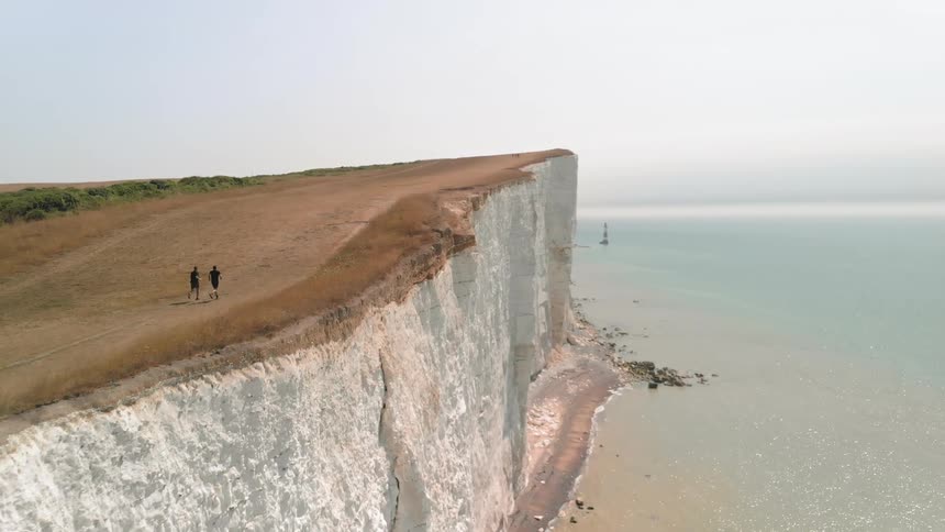 Two Athletes Running by White Cliffs on a Sunny Day