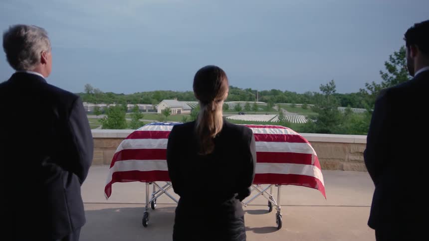 A group of people are looking at a soldiers casket