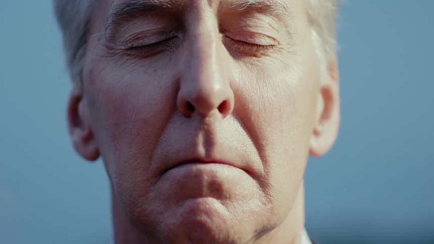 A man closes his eyes outdoors