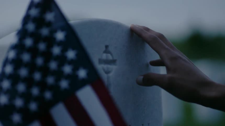 An american flag is standing next to a soldiers grave