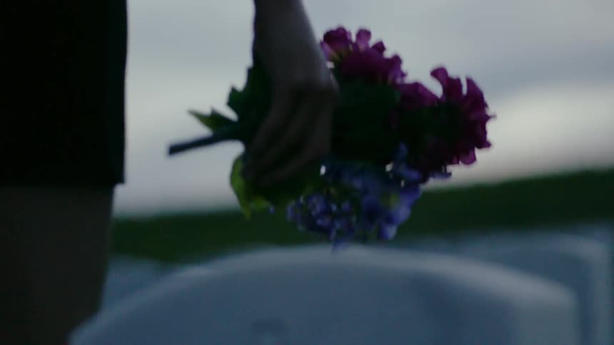 A woman carries flowers in a graveyard