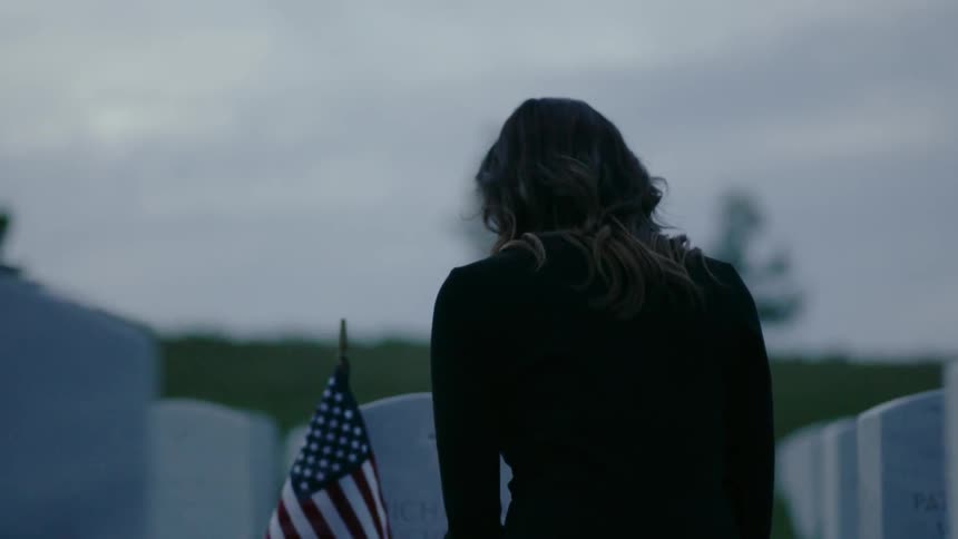 A woman grieves in front of a headstone