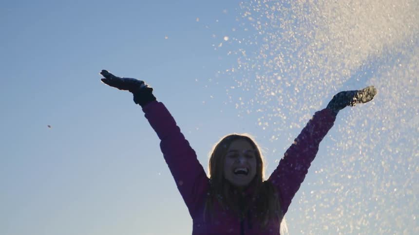A woman playfully throws snow