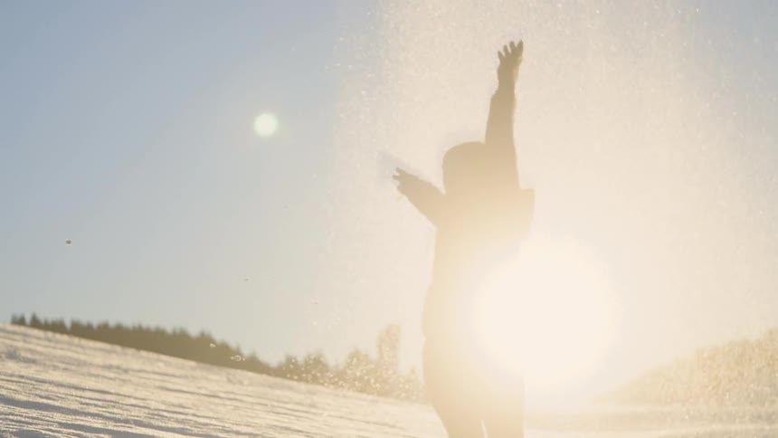 A woman throws a handful of snow into the air