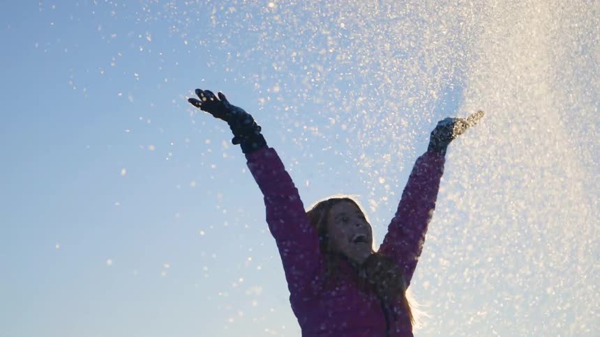 A woman playfully throws snow