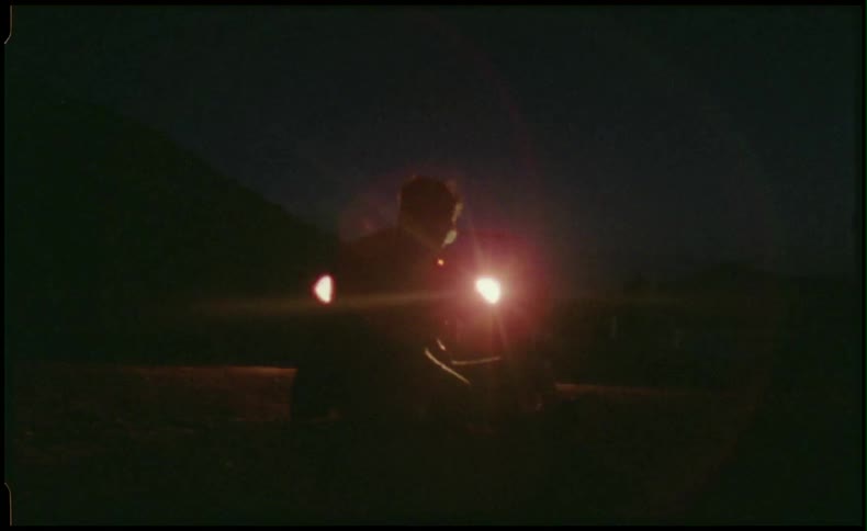 Man walking in front of car headlights and smoking 