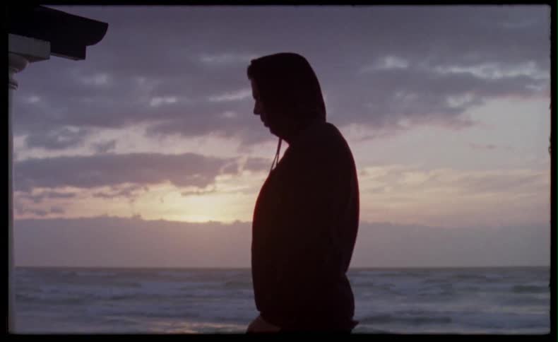 Man lighting a cigarette at sunset by the beach