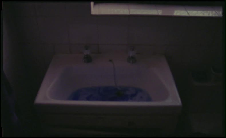 Person pulling a plug on the sink draining blue water