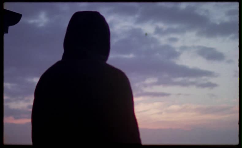 Person wearing a hoodie looking out into beach