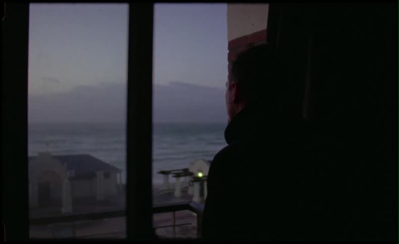 Man looking out of window to the beach