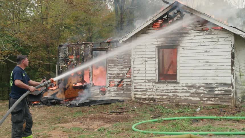 A fireman is spraying water on a burning house