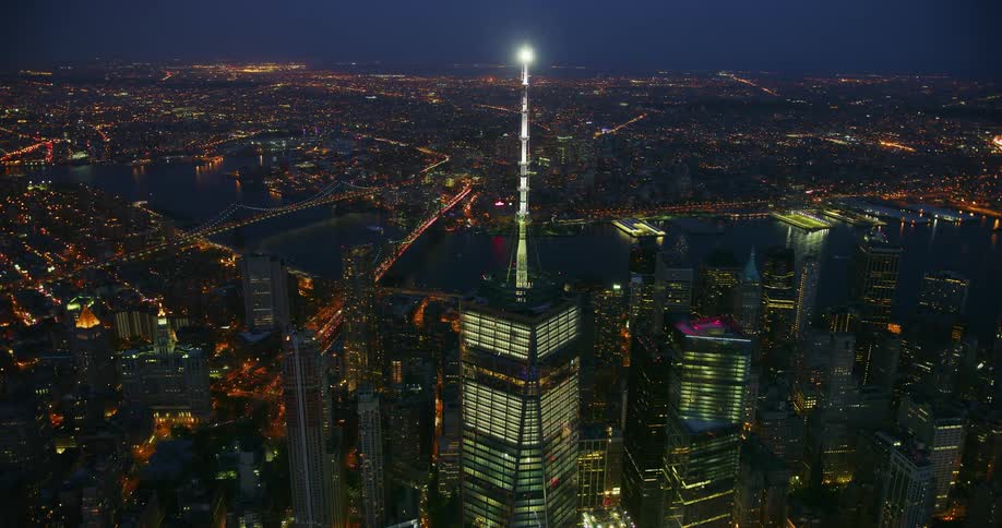 A tall city tower illuminates the night sky