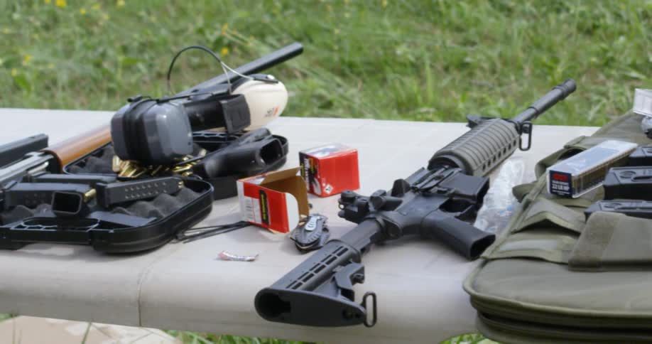 Rifles are laid out on a table outdoors