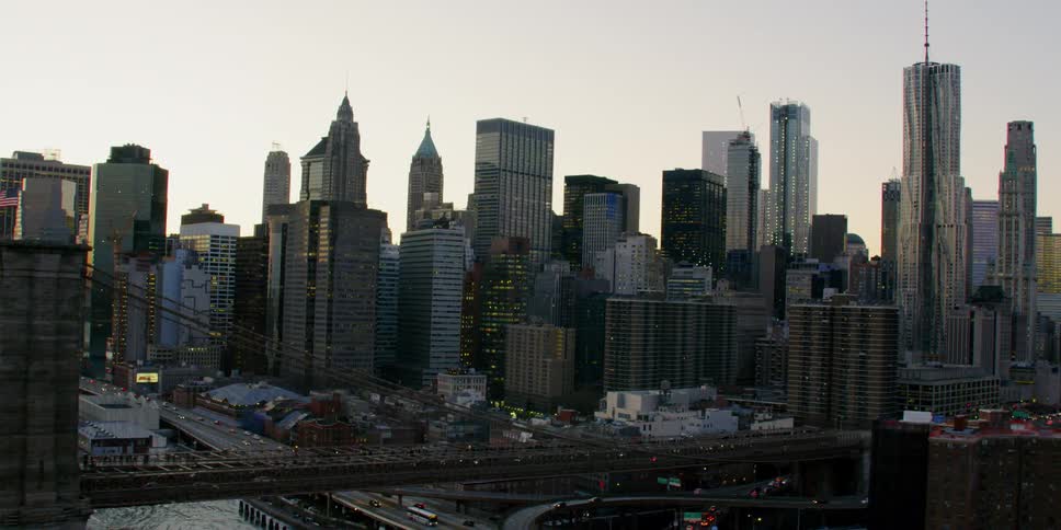 Cars travel over a bridge and on the highway of a city at sunset