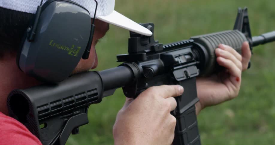 A man fires an assault rifle outdoors