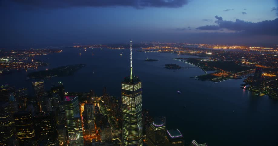 Skyscraper standing tall in a large city next to water at sunset