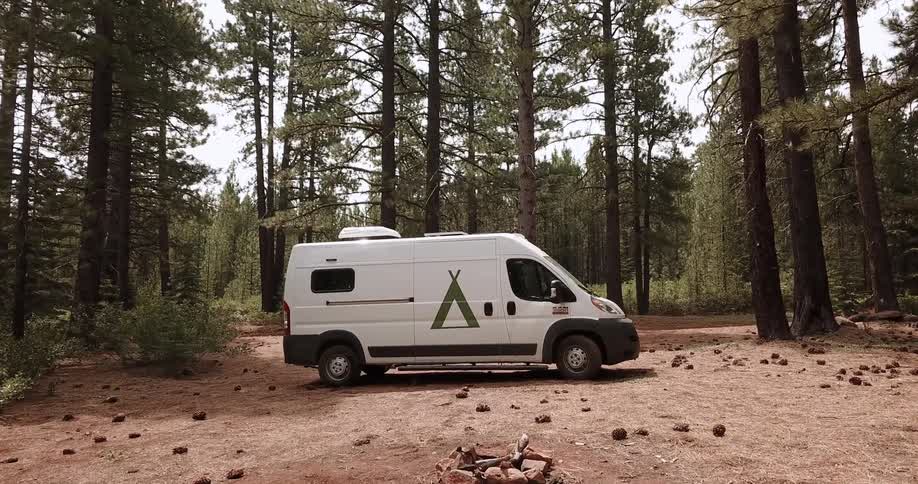 A van sits parked in the forest