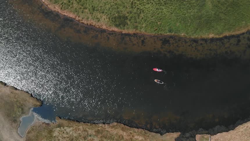 Two people kayak down a stream