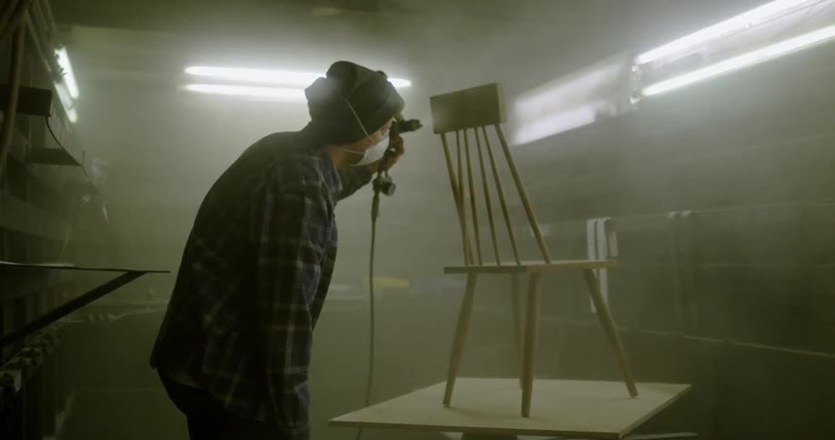 A man sprays paint on a chair