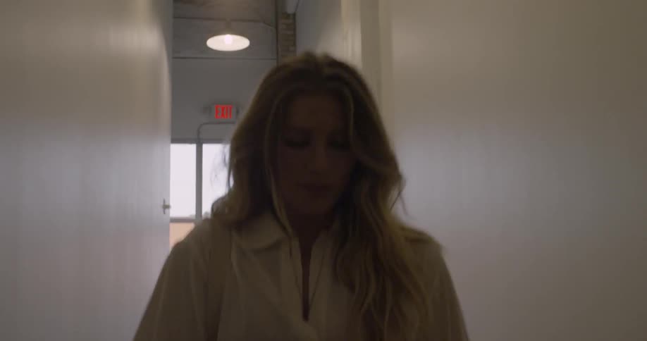 A woman is carrying a painting canvas as she walks through a hallway during the day