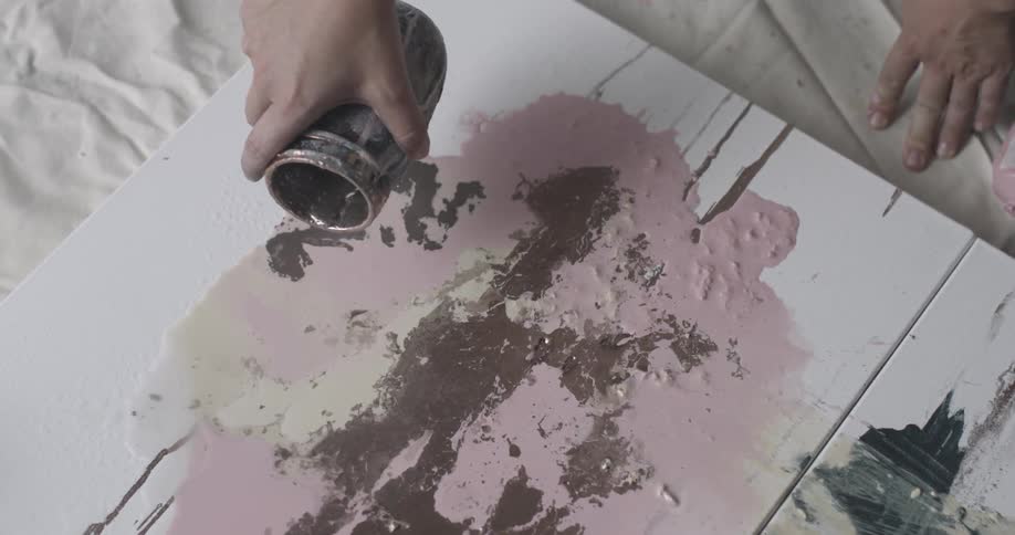 An artist pours paint on a canvas