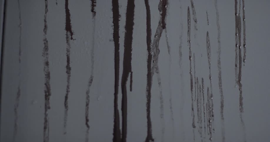 Black paint streams down a wall