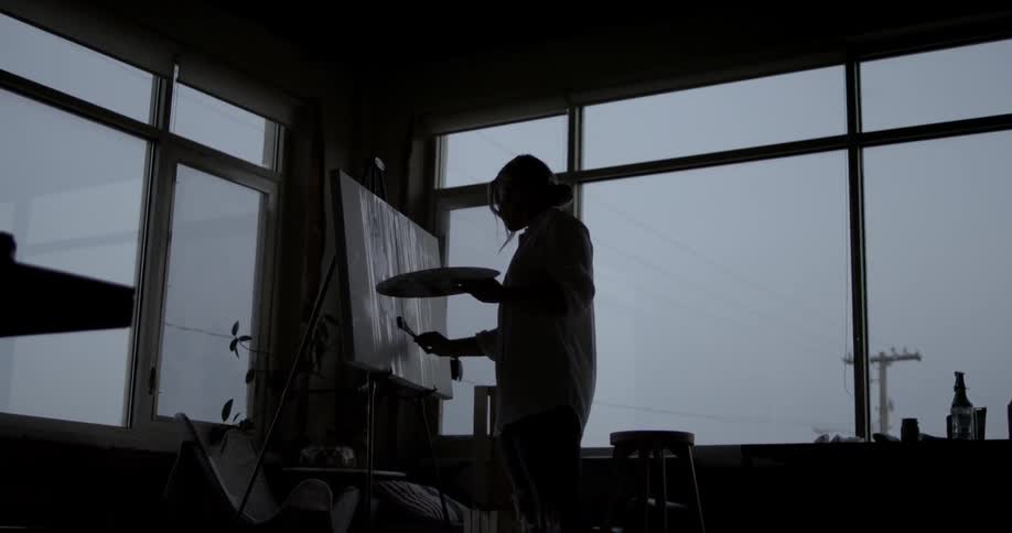 An artist paints on a canvas