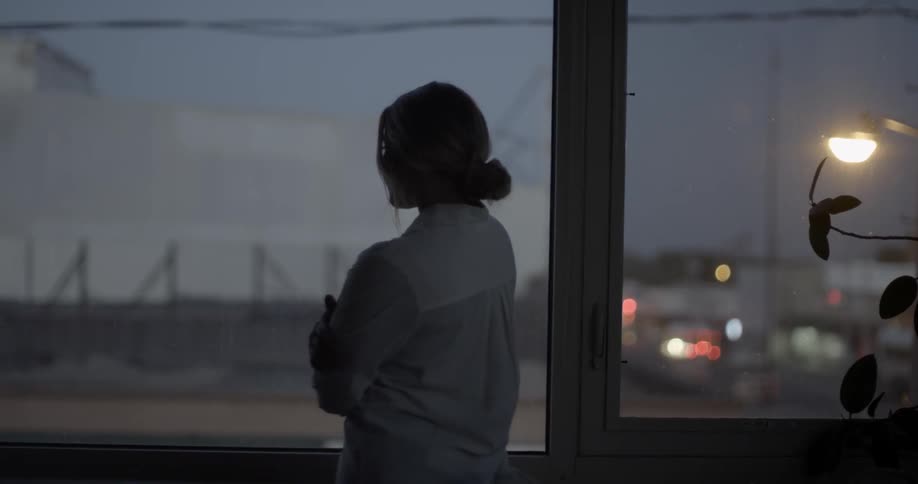 A woman walks towards windows in a studio