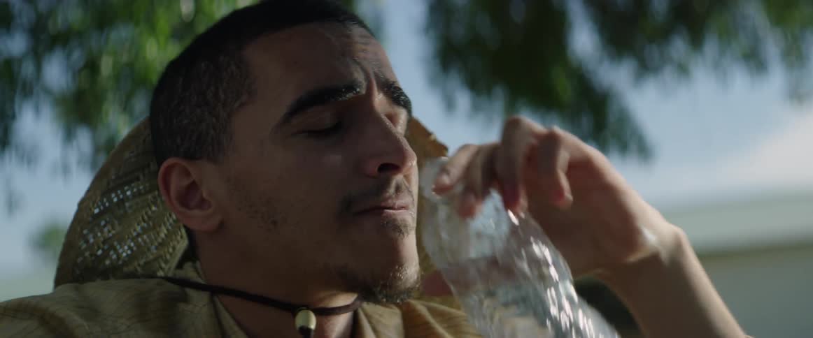 A sweating man takes a drink of water outside