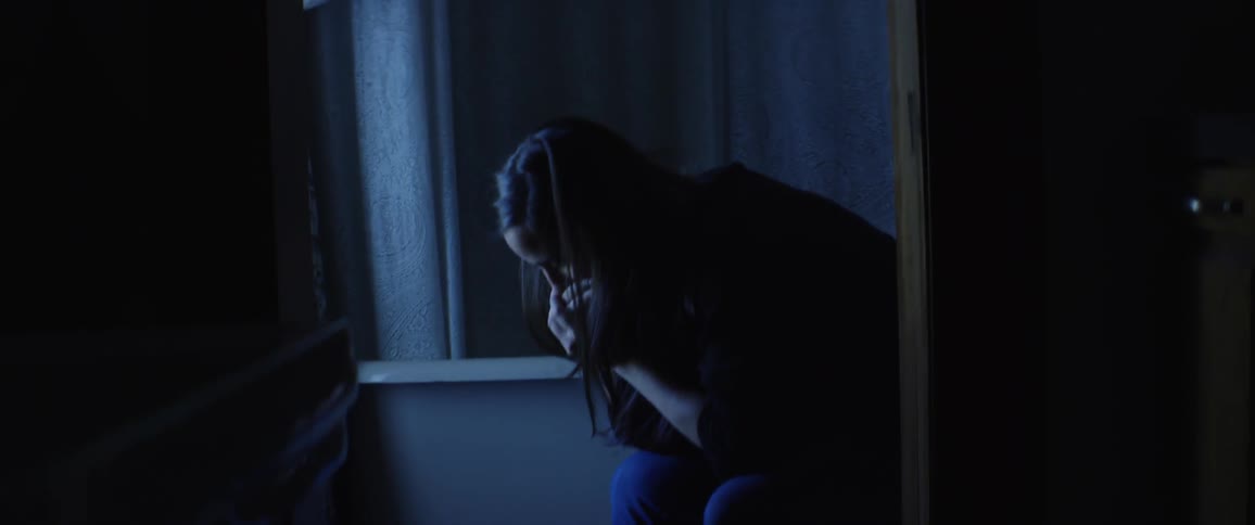 A woman sits distraught in a bathroom