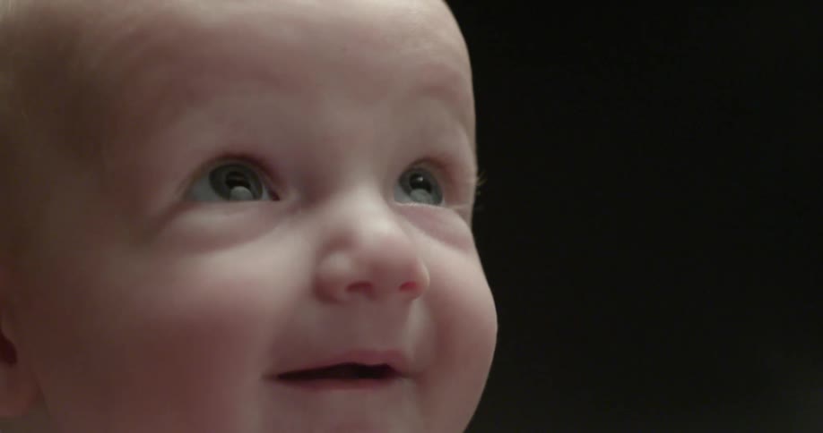 A baby is smiling and blinking its eyes