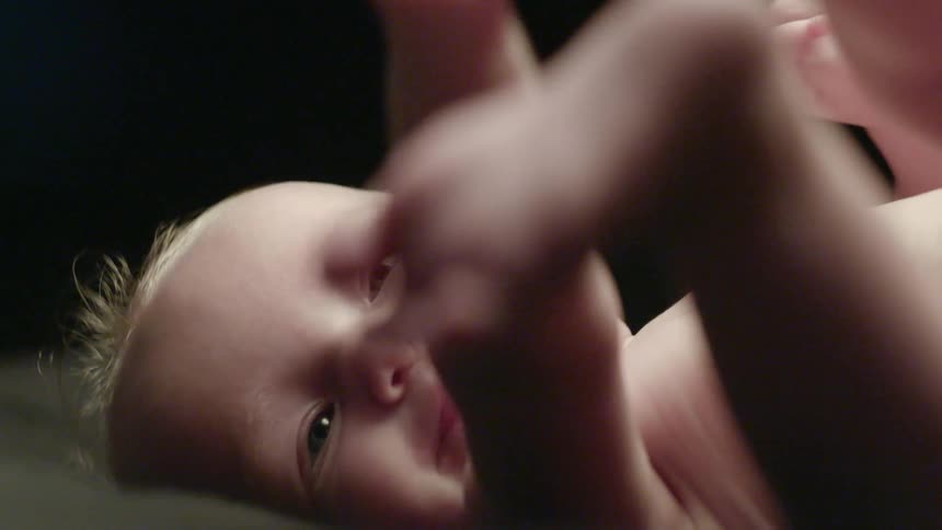 An infant fidgets and feels his feet