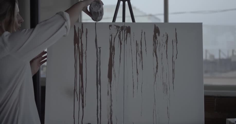 An artist paints on a canvas