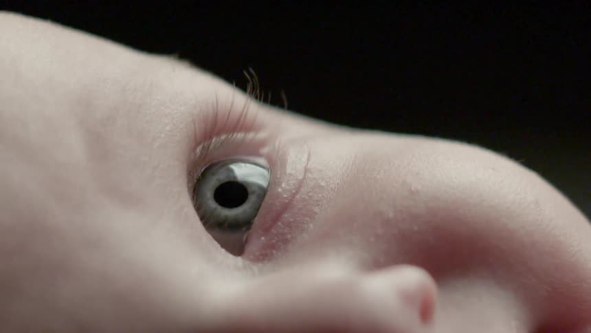 An infant smiles and looks upward
