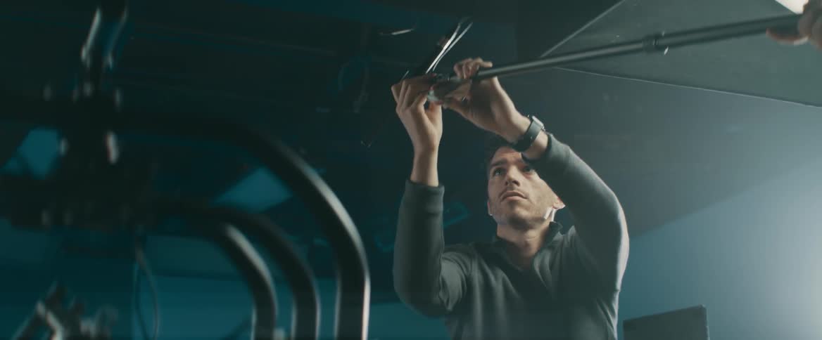Man making an adjustment on a long pole object indoors