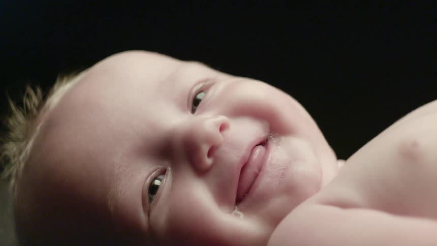 An infant lays and smiles