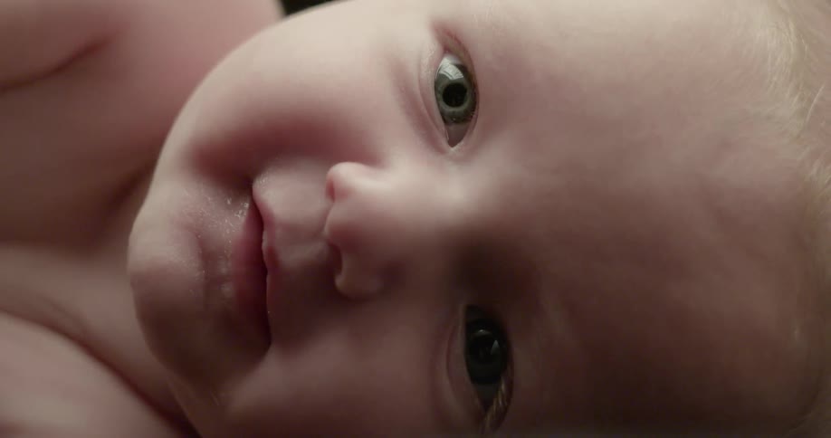 An infant lays in a black room