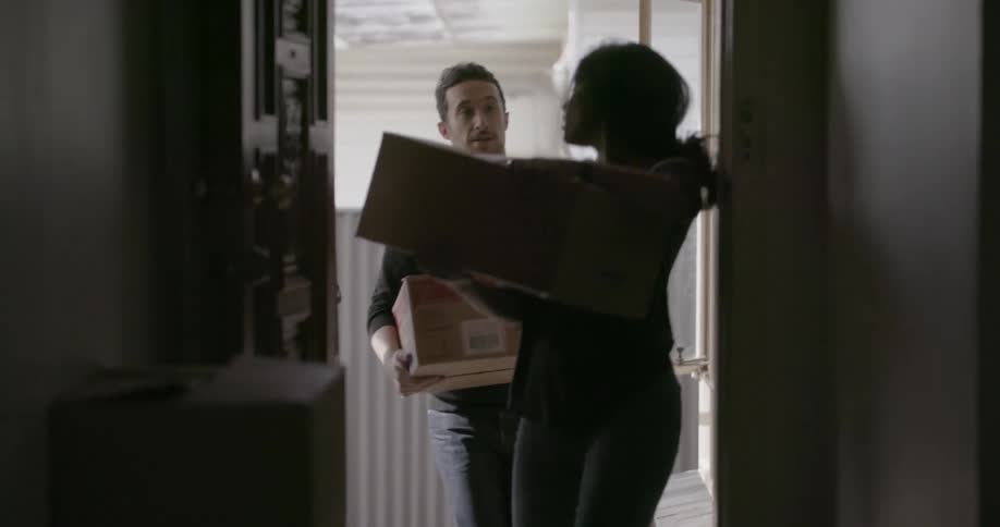 A man and woman pick up boxes and bring them into the house