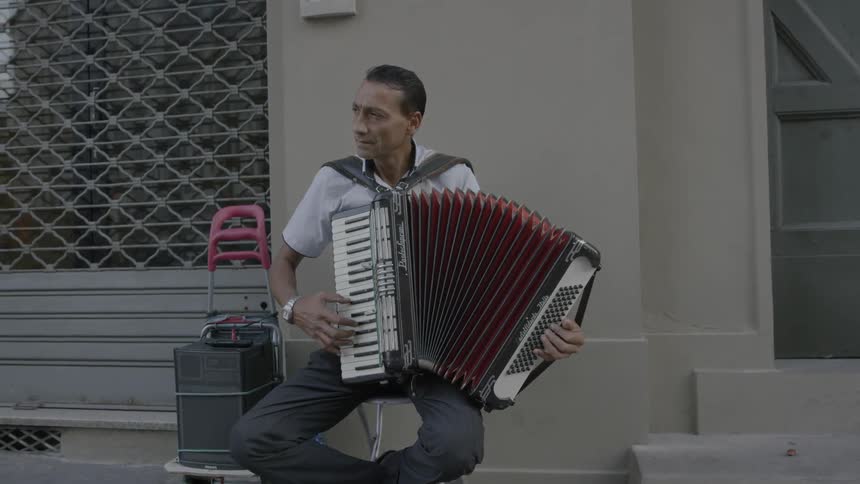 A man plays an accordion on a sidewalk
