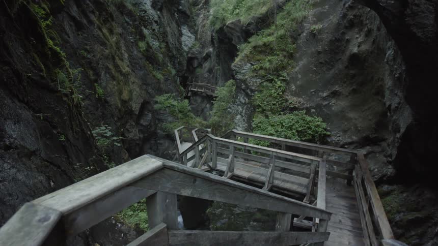 A wooden path and stairs lead into a narrow gorge