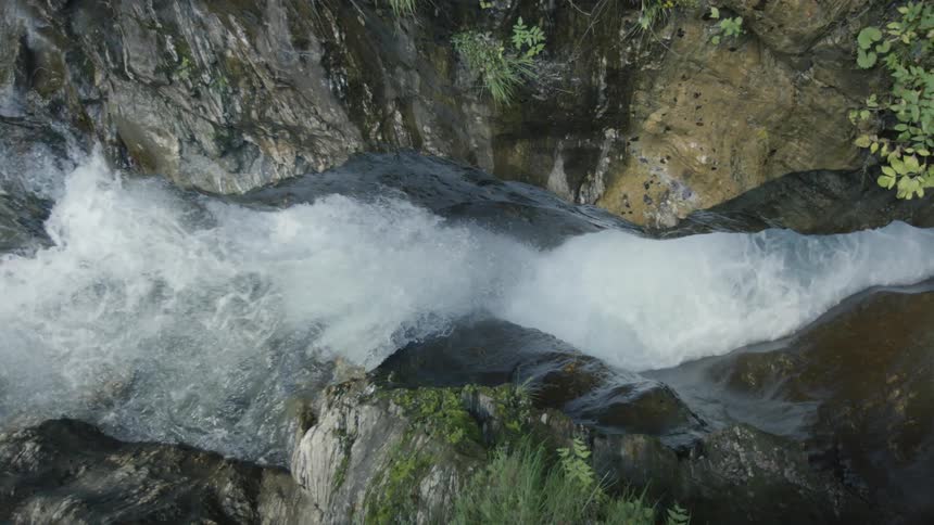 Aerial view looking down upon waterfall flowing down into a river