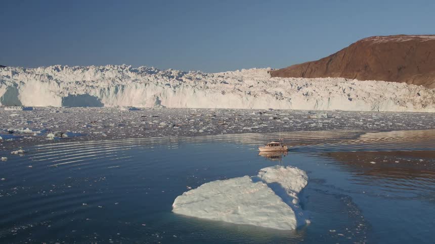 A boat floats on an icy body of water