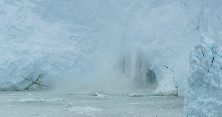 Ice falls off an iceberg formation into the water
