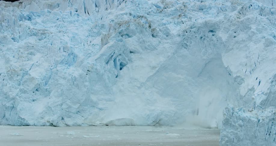 Snow and ice crash down into the water from an iceberg